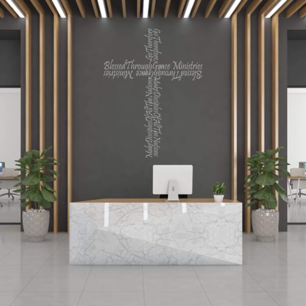 Interior reception desk with gray wall featuring a branded organization name cross